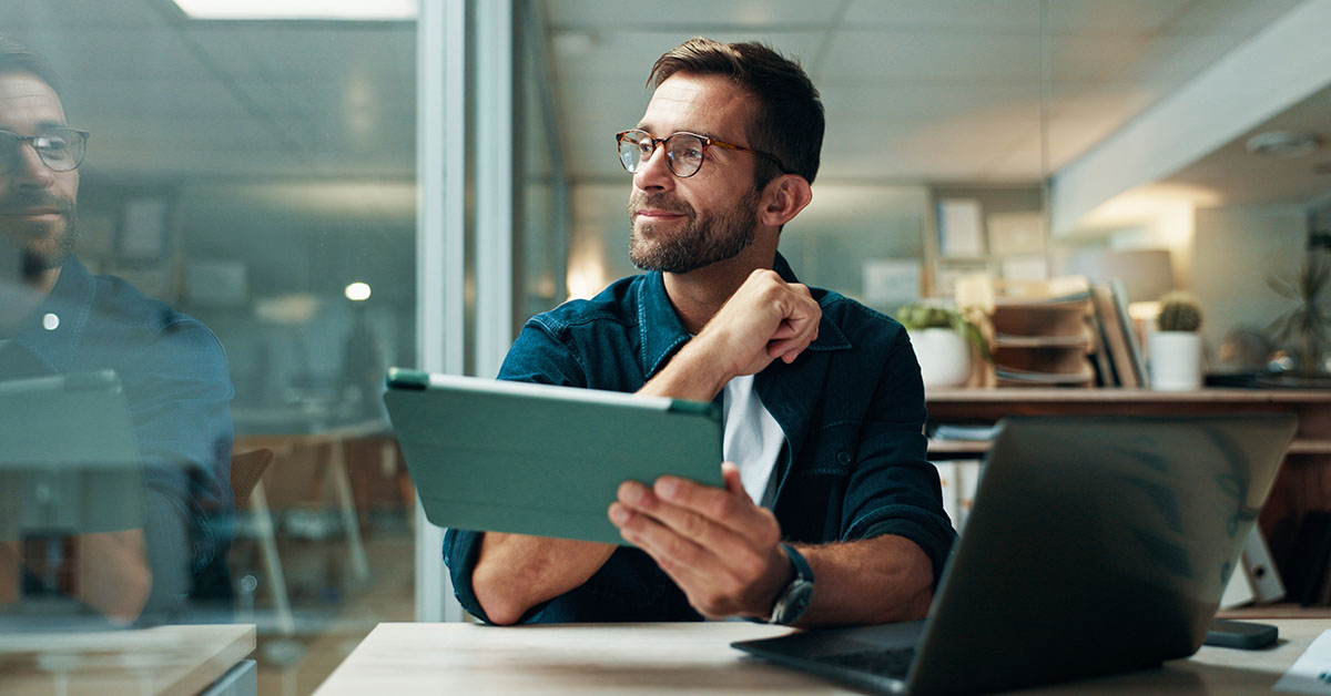 Tablet, thinking and smile with business man in office for planning, ui designer and app review. Developer solutions, reflection and research with person in agency for project idea and startup Search in B2B e-commerce, illustrative picture